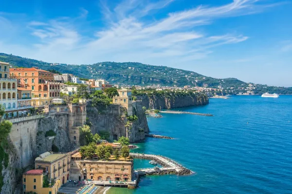 Scenic Mediterranean cliffside town overlooking the ocean with a cruise ship in the distance